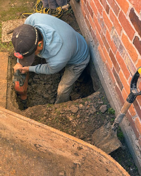 person using a jack hammer in a hole